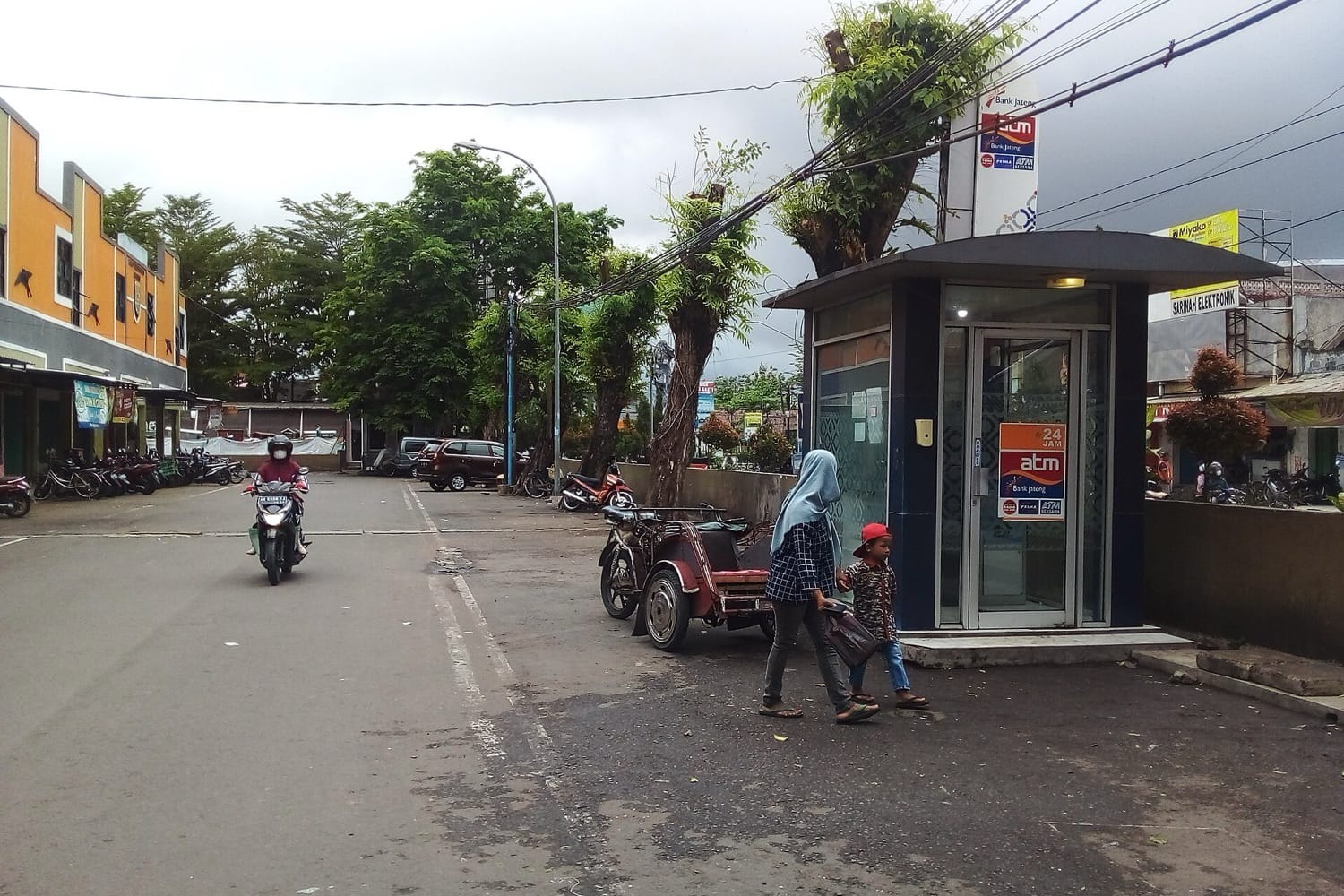 Bilik ATM di tepi jalan dekat Pasar Tumenggungan, Kebumen, dengan seorang ibu dan anaknya melintas