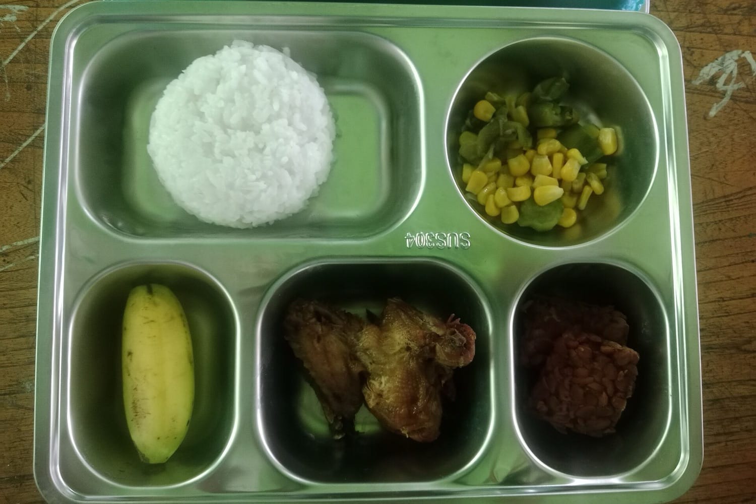 Ompreng makan bergizi gratis berisi nasi, sayur jagung dan buncis, pisang, ayam, dan tempe
