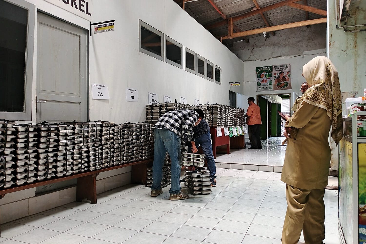 Petugas menata tumpukan ompreng makanan di sebuah dapur penyedia makan bergizi gratis