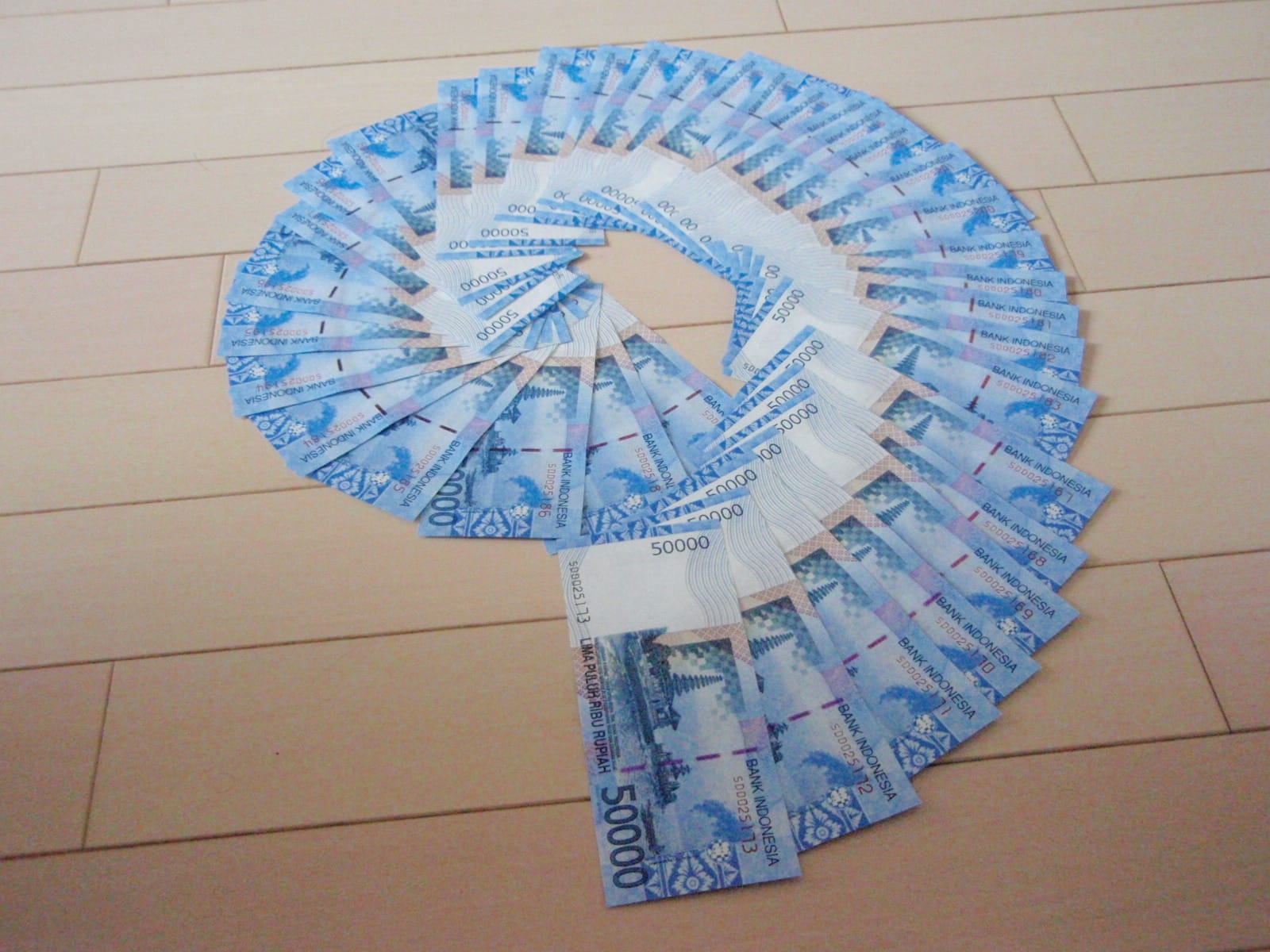 Lembaran uang rupiah pecahan Rp50.000 disusun melingkar di atas lantai