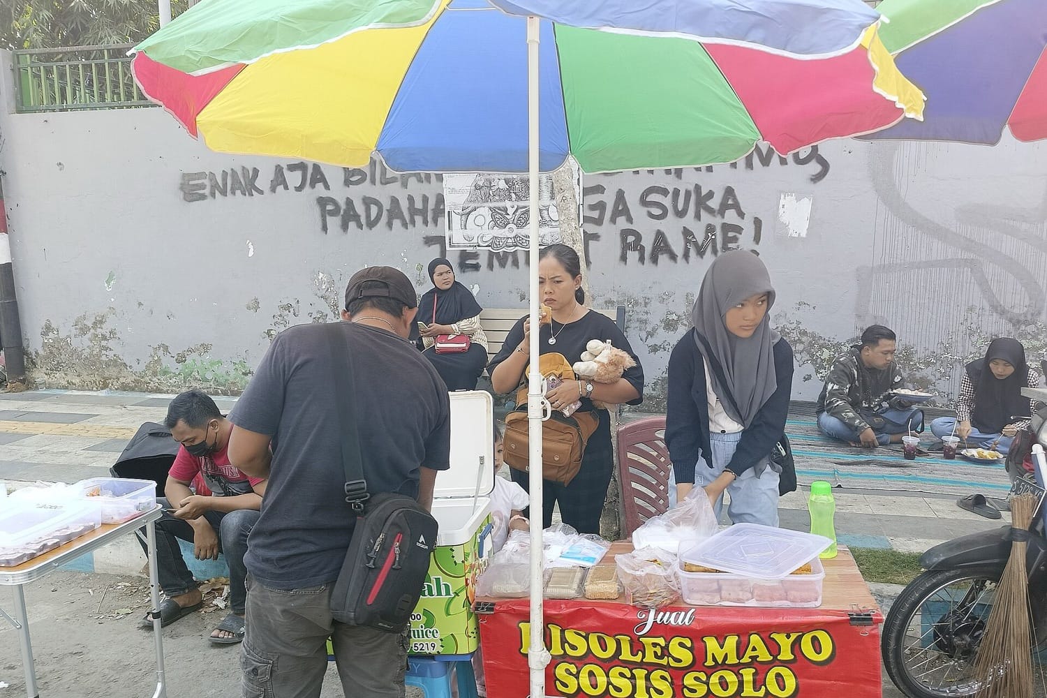 Para pedagang kaki lima melayani pembeli di bawah payung warna-warni di Alun-alun Jombang